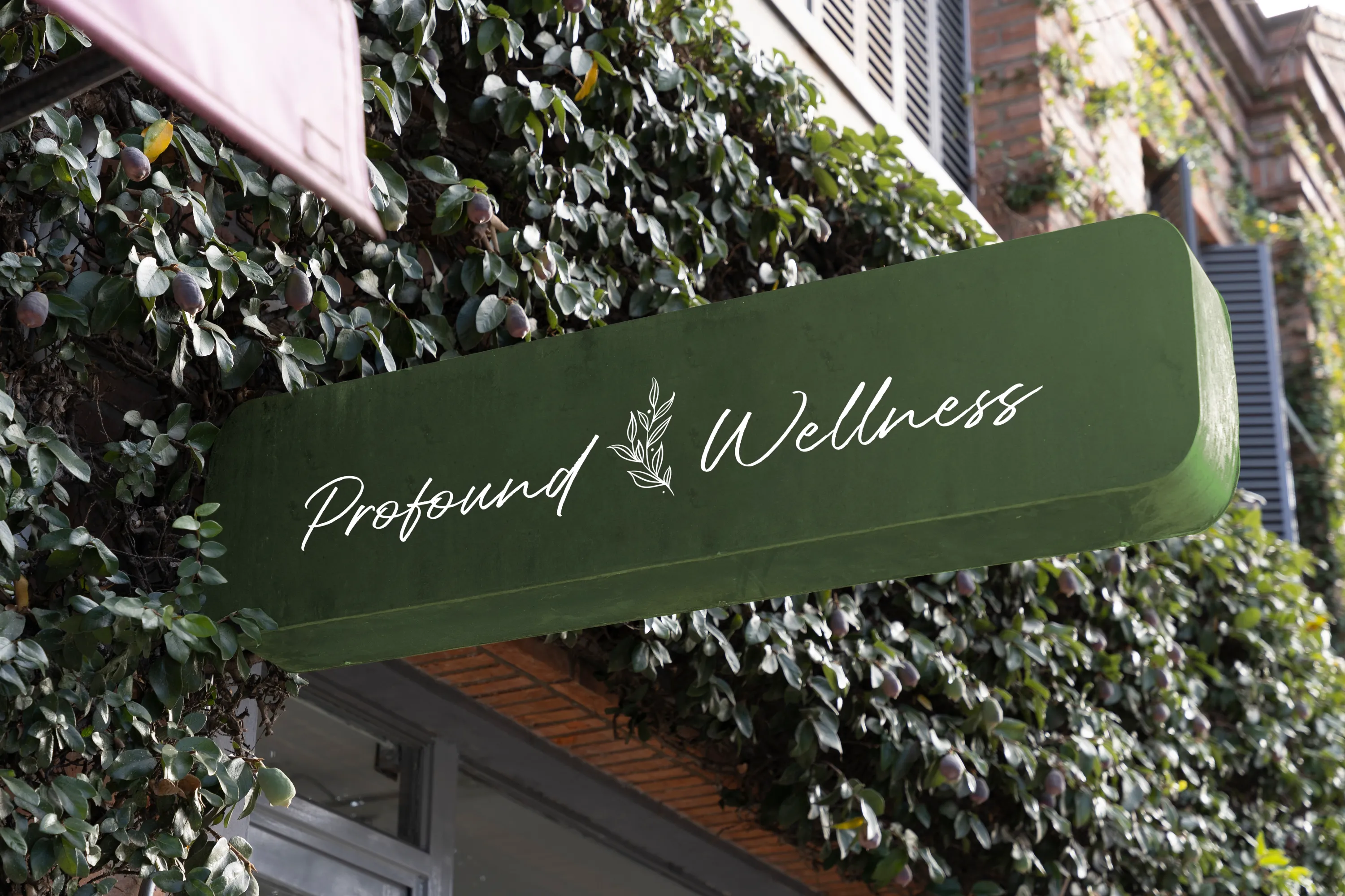 Wellness Brand Storefront Sign Design Profound Wellness logo on a green storefront sign against a wall of greenery for a holistic health company, branding by Dream Wild Studio