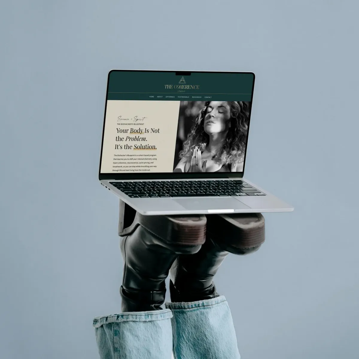Person holding an open laptop displaying a coaching website, website design by Dream Wild Studio.