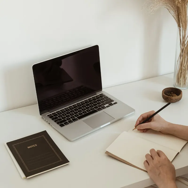 Laptop and notebook on a desk with a business owner taking notes, representing the discovery phase of a brand and website launch with Dream Wild Studio