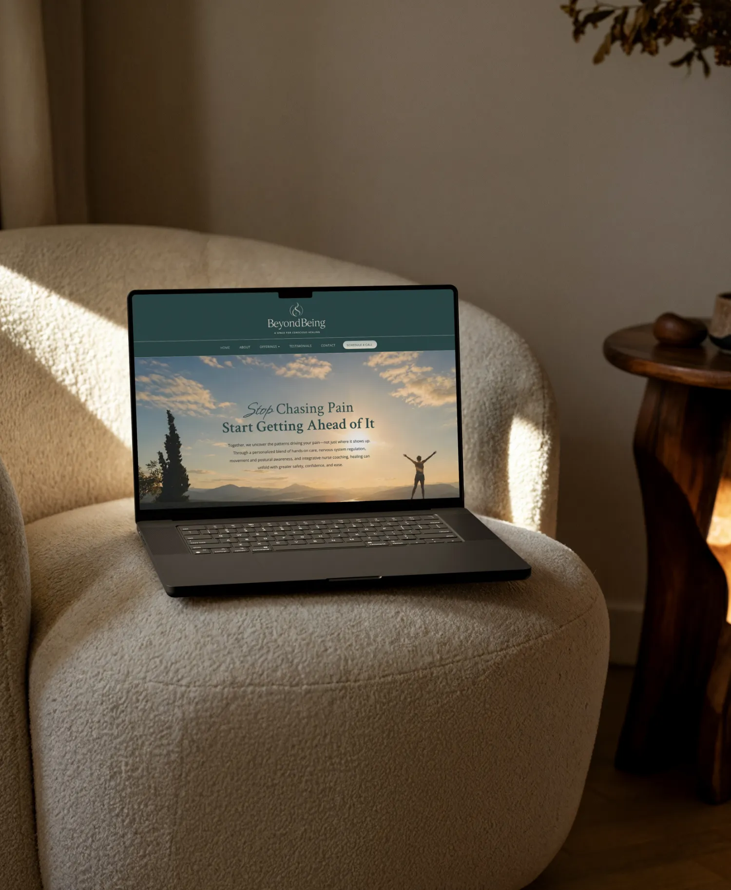 Custom integrative healing website shown on a laptop resting on a neutral chair by Dream Wild Studio
